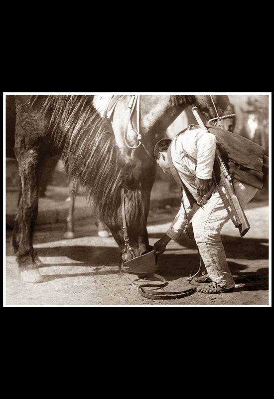 Soldado federal dando agua a su caballo con el casco